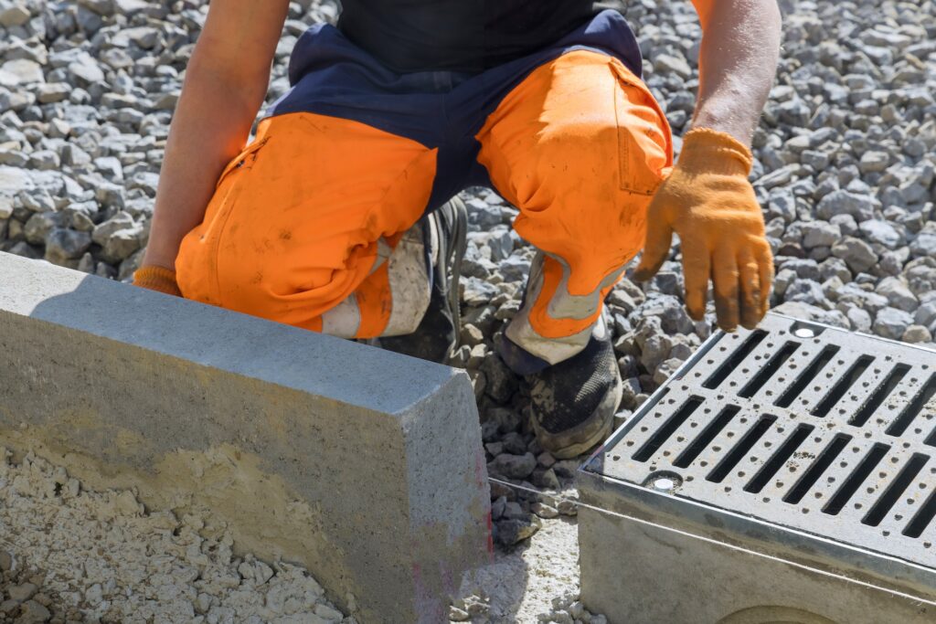 Municipal worker laying water drainage construction on well concrete